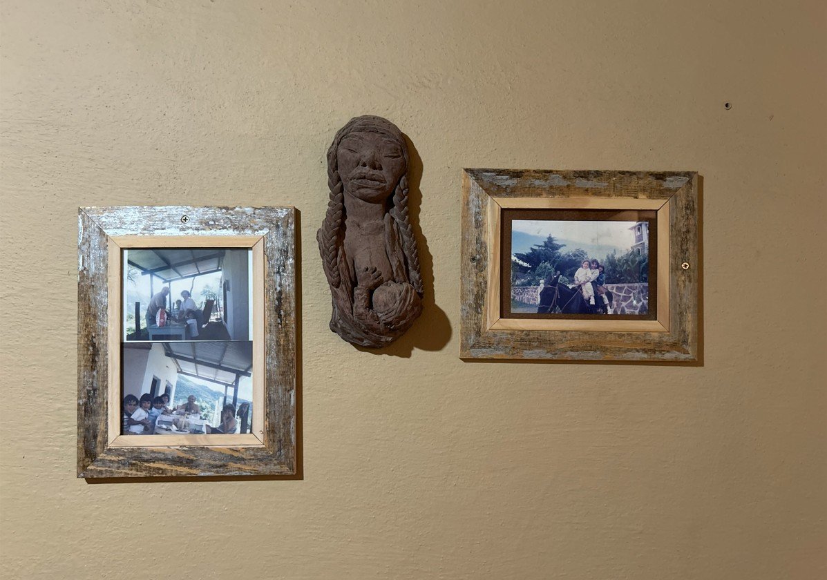 Fotografías antiguas y escultura artesanal en pared rústica.